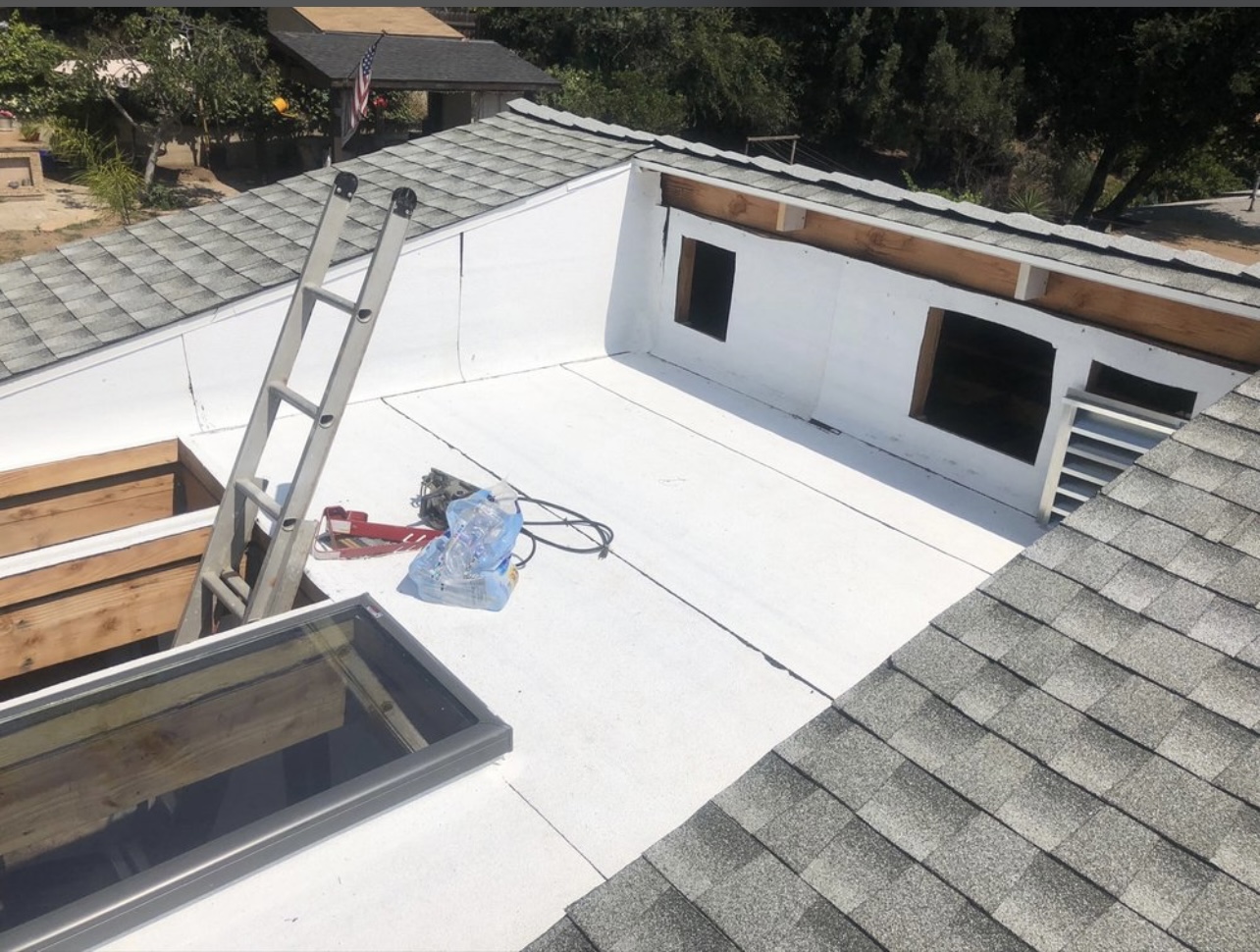 White flat roofing membrane bordered by gray shingles